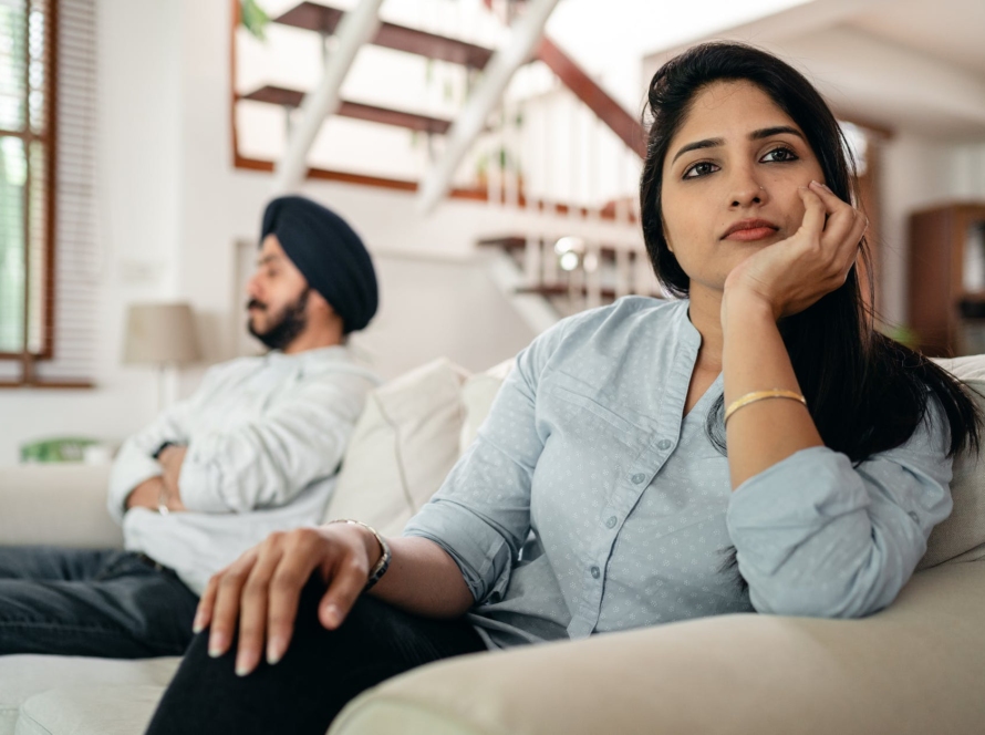 sad young indian woman avoiding talking to husband while sitting on sofa