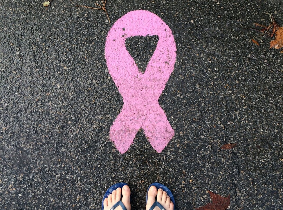 person legs near cancer awareness pink ribbon on asphalt